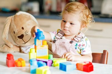 Adorable toddler girl with favorite plush bunny playing...