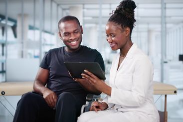 Happy African Doctor With Male Patient In Hospital