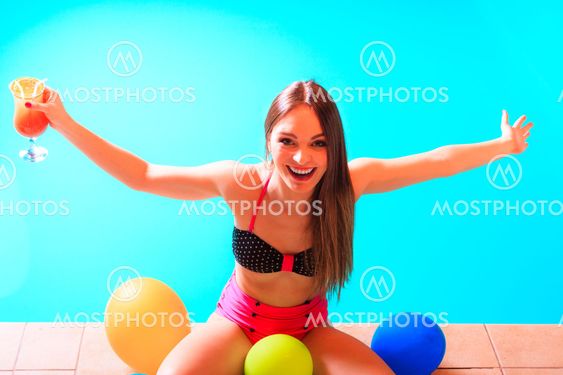 Happy woman with balloons and cocktail at poolside