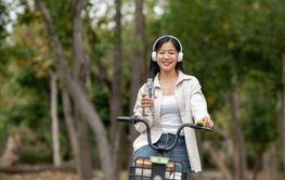 An asian woman is holding a clear water bottle on bicycle...