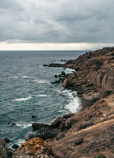 Coastal landscape featuring rocky cliffs, calm waters,...