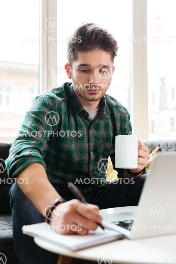 Vertical image of man with laptop on sofa