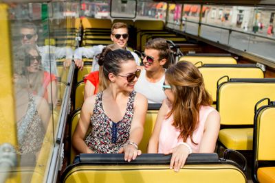 group of smiling friends traveling by tour bus