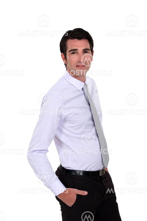 Confident young businessman stood with hands in his pockets