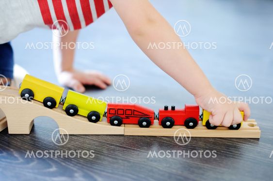 Toddler boy playing with toy wooden train at home