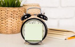 Reminder note and black old-fashioned alarm clock