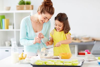 happy mother and daughter baking muffins at home