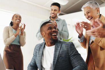 Man, celebration and team with applause by laptop for...