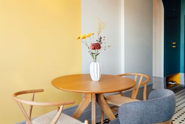 Close-up of a round wooden table with a vase of flowers....