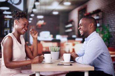 Laughing Male And Female Sitting In Cafe Drinking Coffee
