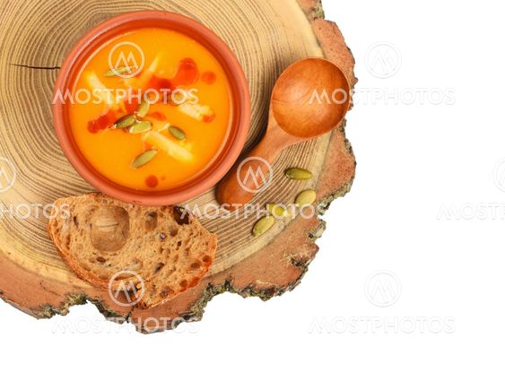 Bowl of pumpkin soup on wood cut over white