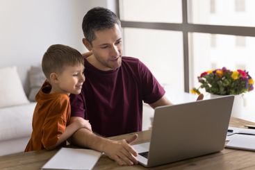 Dad and son using laptop at home