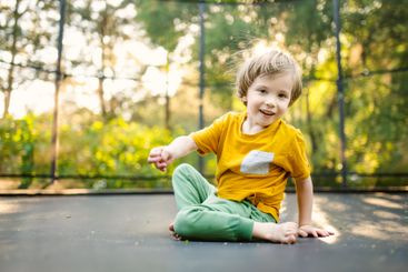 Little boy jumping on a trampoline in a backyard on warm...