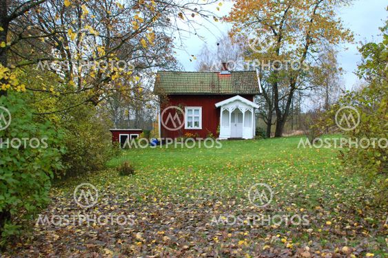 Röd liten stuga i höstmiljö