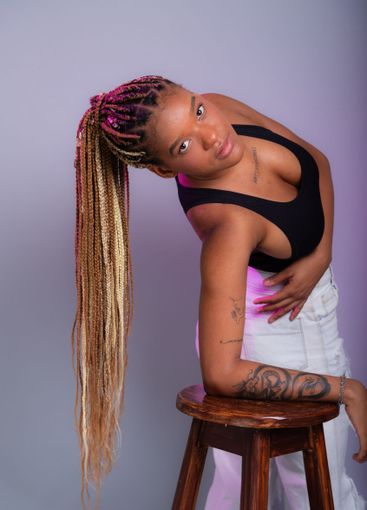 Brunette model with braids in her hair, wearing white...