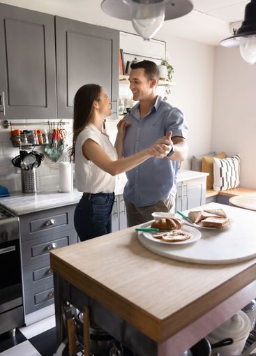 Happy romantic young couple cooking and dancing at home