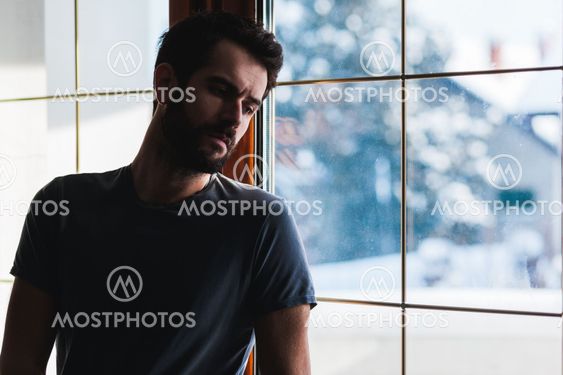 Young sad mad standing by the window
