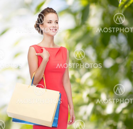 smiling elegant woman in dress with shopping bags