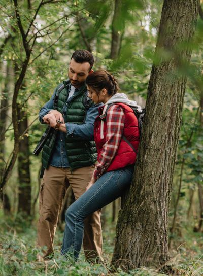 couple of travelers with backpacks checking time in forest