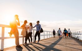 Friends standing on pier at sunset