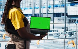 Smart factory technician manages robotic arms using...