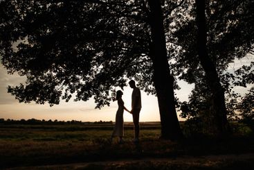 In a tranquil setting at dusk, a couple stands...