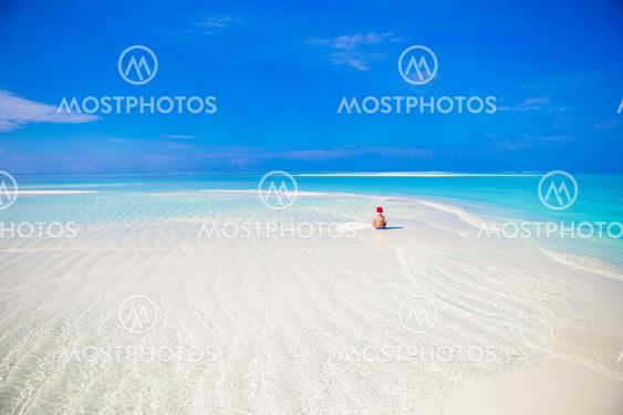 Little girl in Santa hat on the beach during vacation