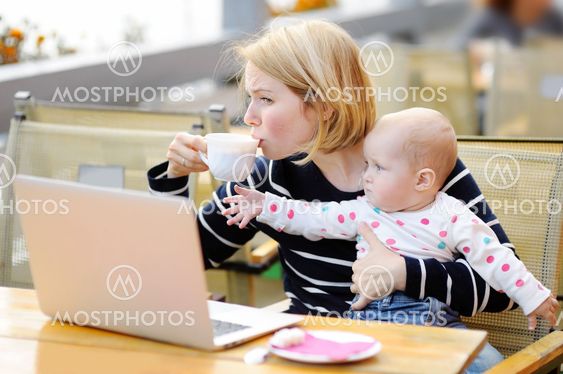 Tired young mother holding 6-month daughter and drinking...