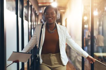 Businesswoman, headphones and dance in office to music,...