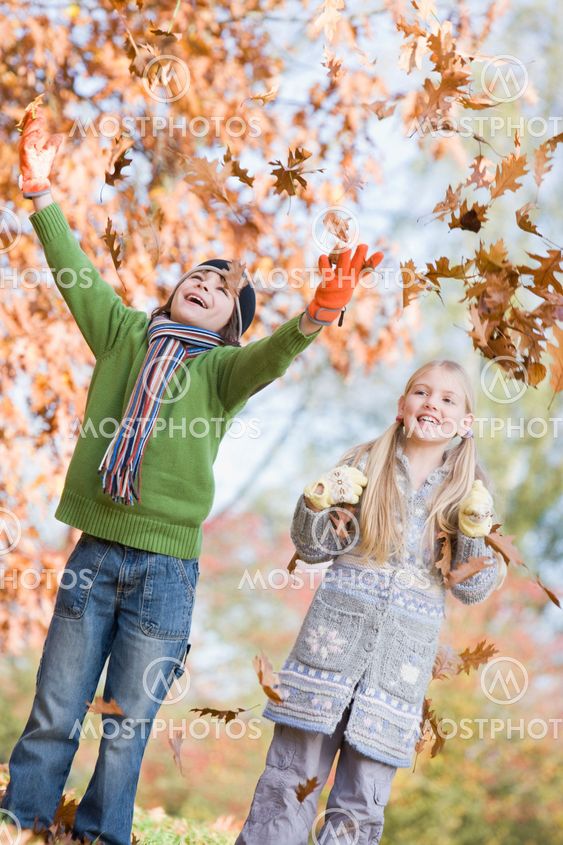 Two children throwing leaves in the air