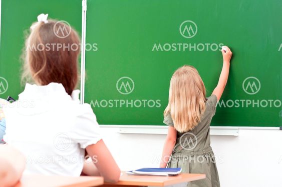 school girl writes on the blackboard