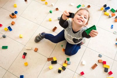 girl playing with colored bricks scattered on the floor