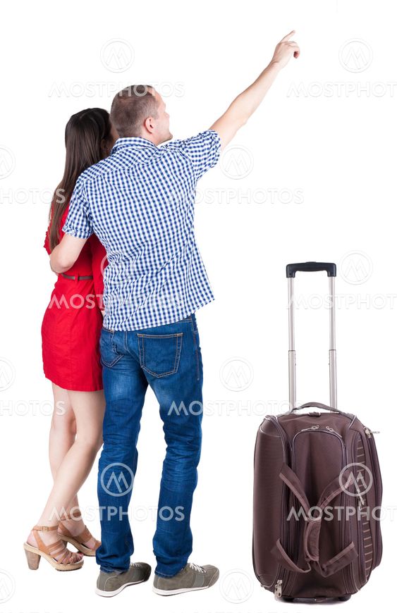 young couple traveling with suitcas and pointing at wal...