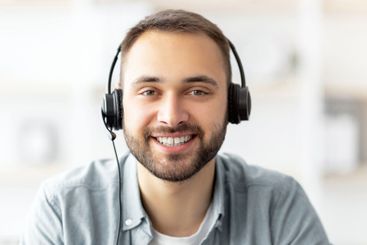Cheerful young Caucasian guy in headphones having online...