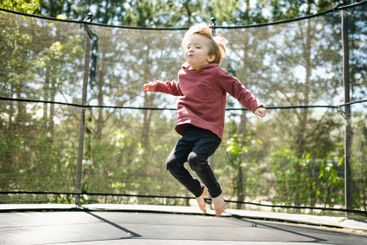 Little boy jumping on a trampoline in a backyard on warm...