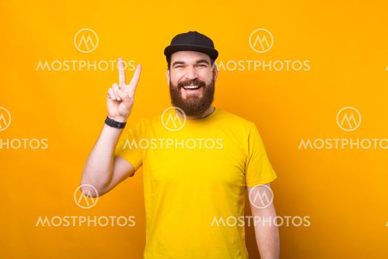 Photo of a cheerful young man is showing the peace sign...