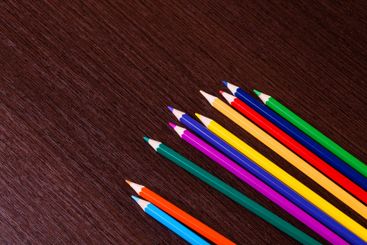 Colorful pencils arranged in a line on a wooden surface...