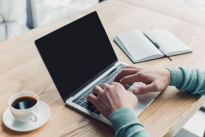 cropped view of man typing on laptop with blank screen...