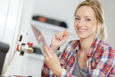 female plumber working on central heating boiler
