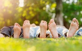 Family of for lying down on the meadow with naked feet.