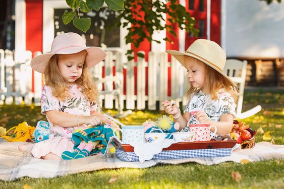 Two little girls sitting on green grass