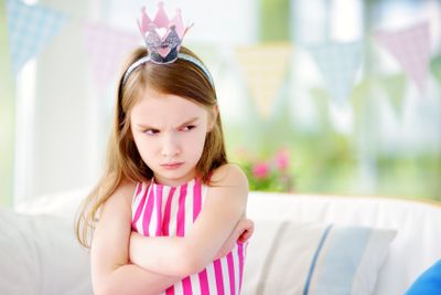 Moody little girl wearing princess tiara feeling angry...