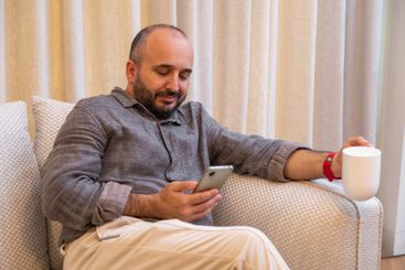 A man enjoys coffee and watches the news on his phone.