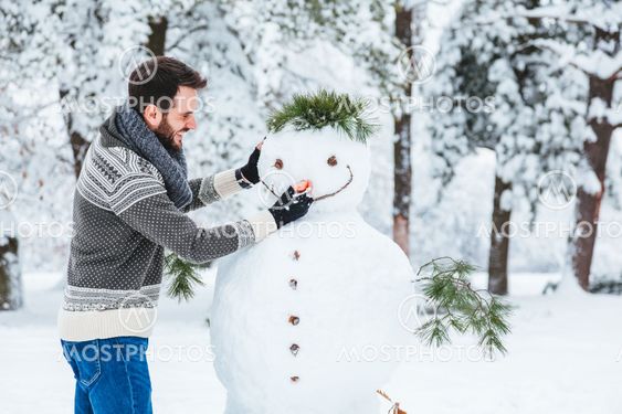 Young man making snowman in the park