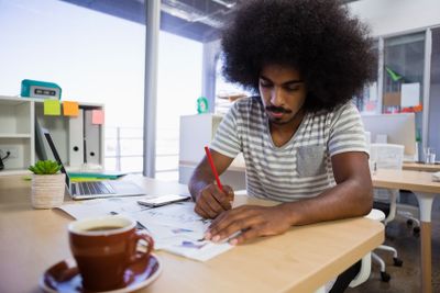Concentrated man writing on document at office