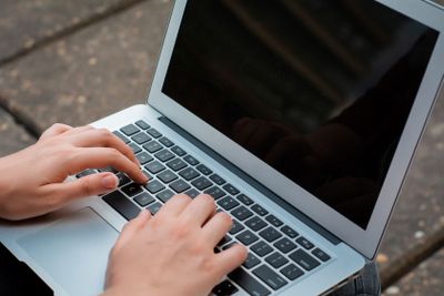 Young student using laptop outdoors. 
