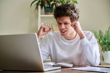 Happy young guy looking at computer, emotion of joy...