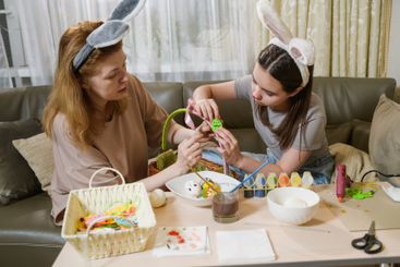 Mother and daughter decorating Easter basket at home.