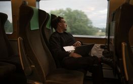 Man with laptop sitting on train