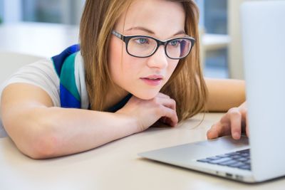 Pretty, female college student in a library, looking for...